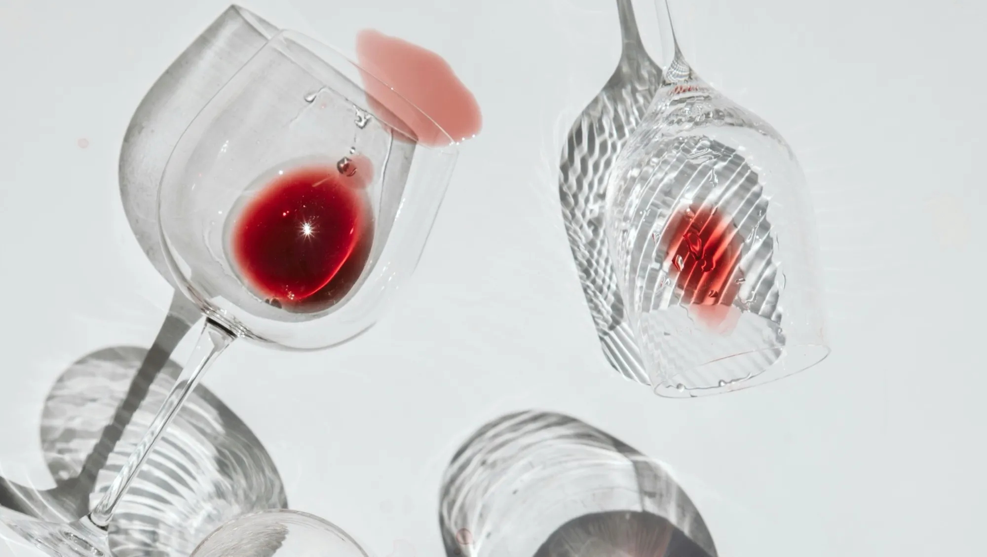 Deux verres à vin renversés sur une surface blanche, avec des taches de vin rouge et rosé